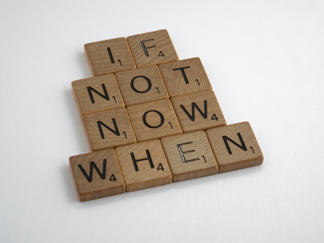 Scrabble tiles on a white background spell out "If not now when"